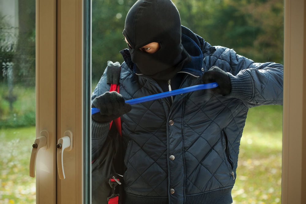 A burglar striving to open a window to a house