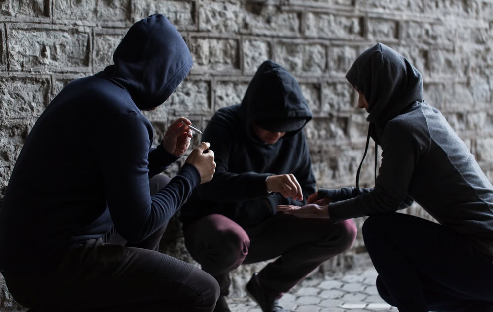 substance abuse, addiction and bad habits concept - close up of young people smoking cigarettes and using drugs outdoors